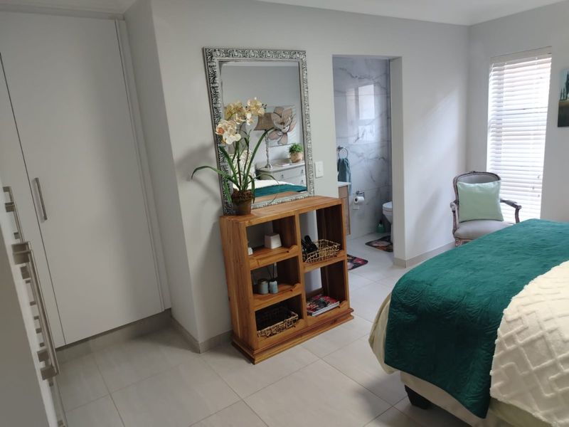 A well-maintained bedroom featuring tiled flooring, built-in cupboards, and direct access to an en-suite bathroom with modern finishes.