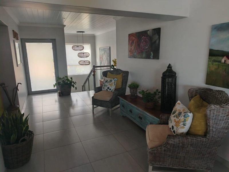 A bright and welcoming entrance hall featuring large format floor tiles, a high tongue and groove ceiling, and a modern frosted glass front door.