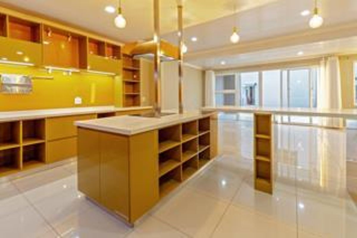Modern kitchen featuring a central island, ample built-in cabinetry, stone countertops, and sleek tiled flooring in an open-plan layout.