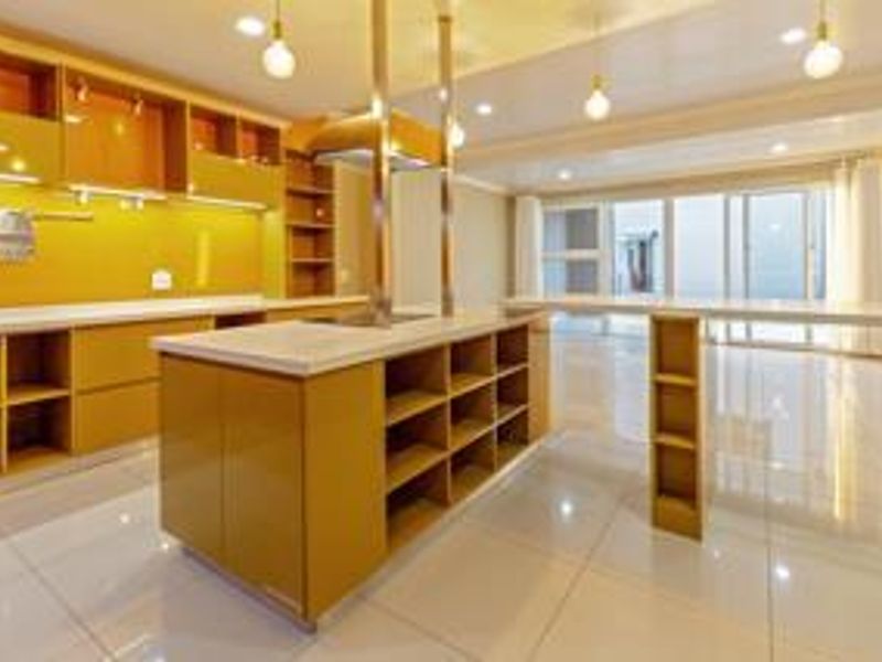 Modern kitchen featuring a central island, ample built-in cabinetry, stone countertops, and sleek tiled flooring in an open-plan layout.