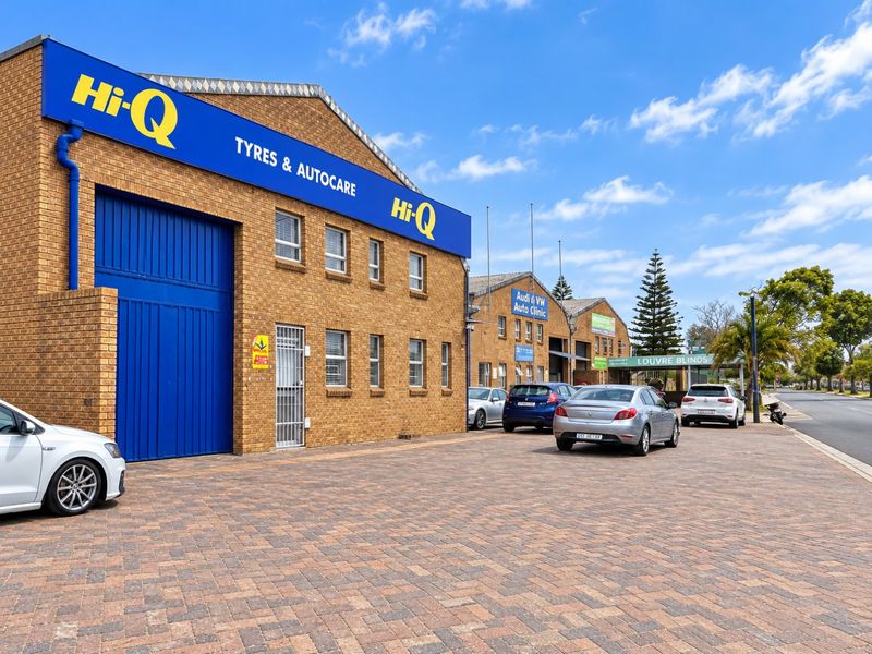 Front exterior view of a commercial industrial property featuring brick facade, large roller door access, and paved parking area.