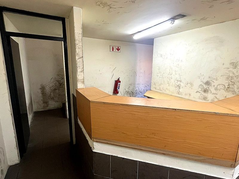 An industrial entry area featuring a built-in reception counter, requiring significant cosmetic refurbishment and wall repairs to restore the space.