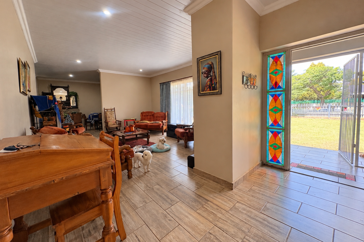 Spacious living area featuring wood-look tiled flooring, a distinctive stained glass door panel, and direct access to the outdoor garden space.