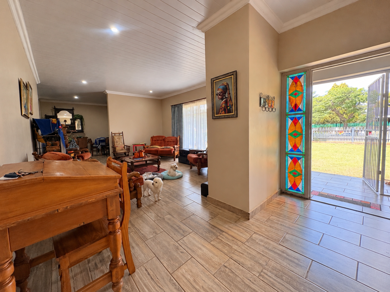Spacious living area featuring wood-look tiled flooring, a distinctive stained glass door panel, and direct access to the outdoor garden space.