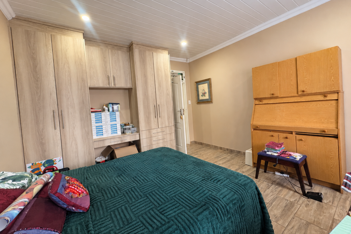 A well-maintained bedroom featuring extensive built-in cabinetry, wood-look tile flooring, and a classic tongue and groove ceiling with recessed lighting.