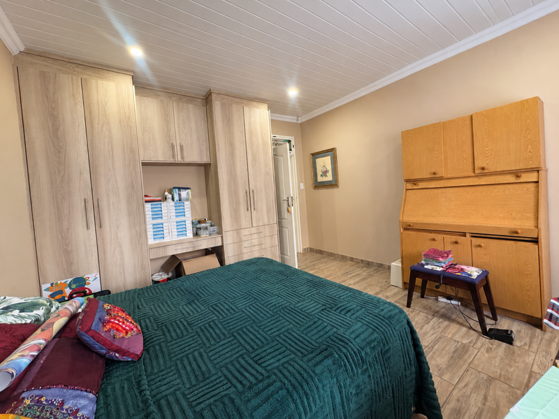 A well-maintained bedroom featuring extensive built-in cabinetry, wood-look tile flooring, and a classic tongue and groove ceiling with recessed lighting.