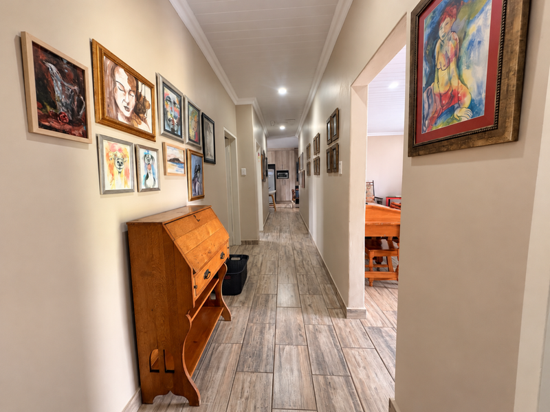 A well-maintained hallway featuring wood-look tile flooring, recessed ceiling lighting, and decorative ceiling paneling, providing a clean transition between living spaces.