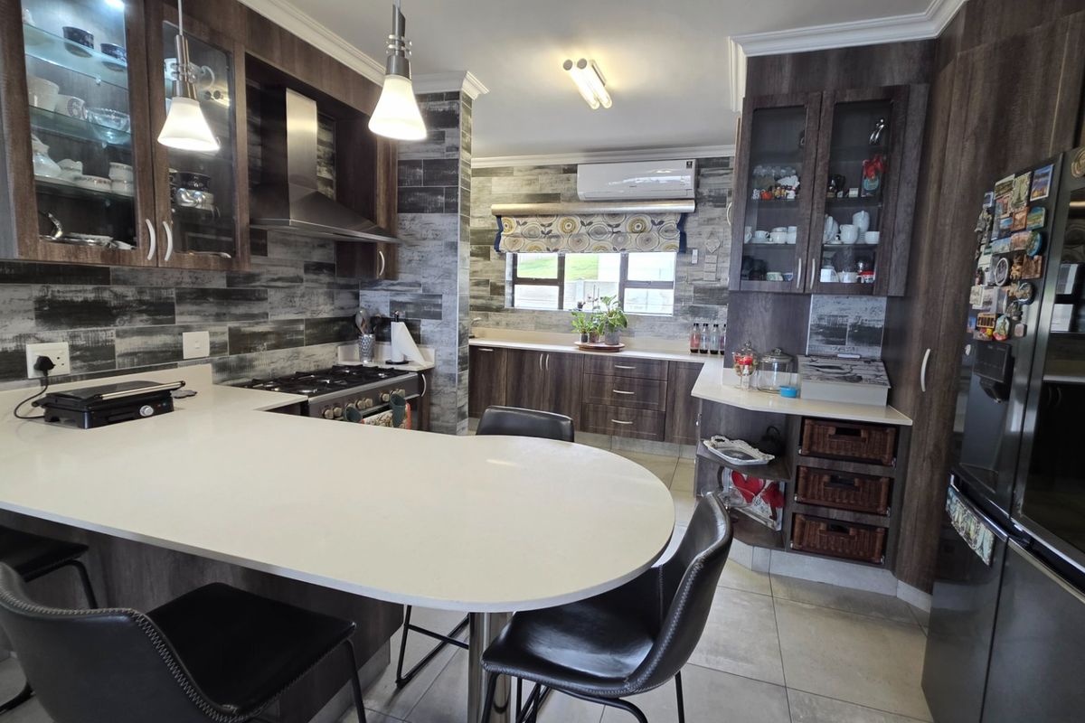 Modern kitchen featuring dark wood cabinetry, stone countertops, a gas hob with extractor, and integrated display shelving, offering a functional and stylish cooking space.