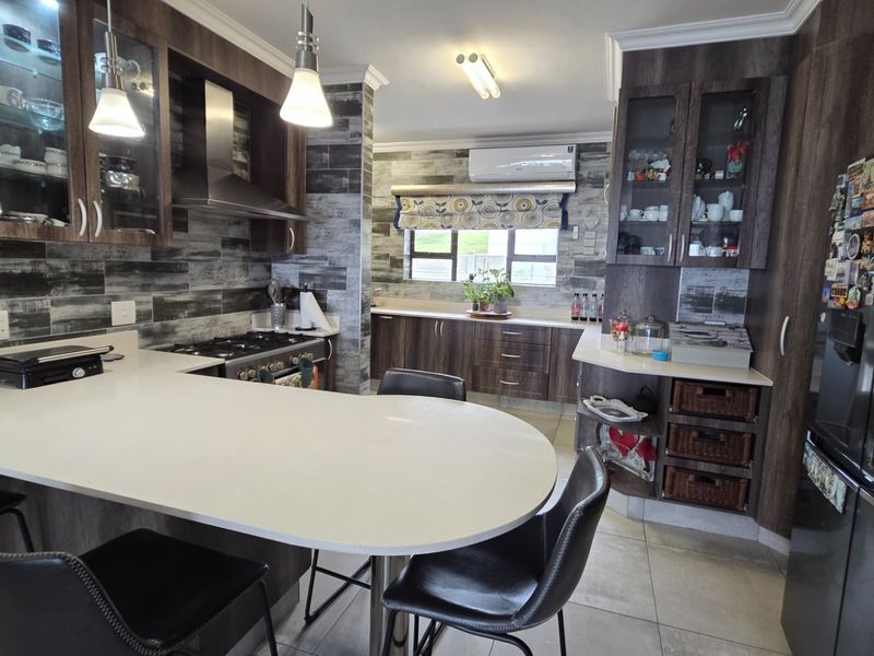 Modern kitchen featuring dark wood cabinetry, stone countertops, a gas hob with extractor, and integrated display shelving, offering a functional and stylish cooking space.