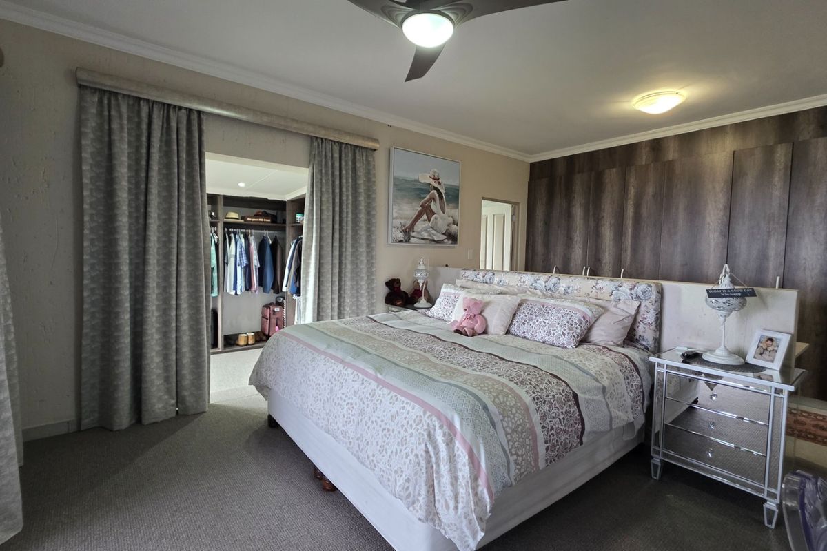 Spacious bedroom featuring built-in wooden cabinetry, a dedicated walk-in closet area, and a ceiling fan, offering a comfortable and well-maintained living space.