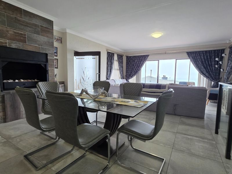 Spacious open-plan living and dining area featuring a modern stone-clad built-in fireplace and large sliding doors that provide ample natural light.