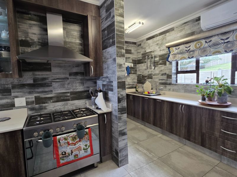 Modern kitchen featuring dark wood cabinetry, stone countertops, gas stove with stainless steel extractor, and contemporary tiled wall finishes.