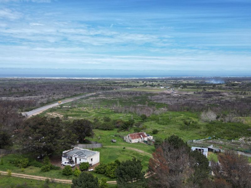 Aerial view of a rural farm property featuring multiple structures, expansive land, and distant coastal views.