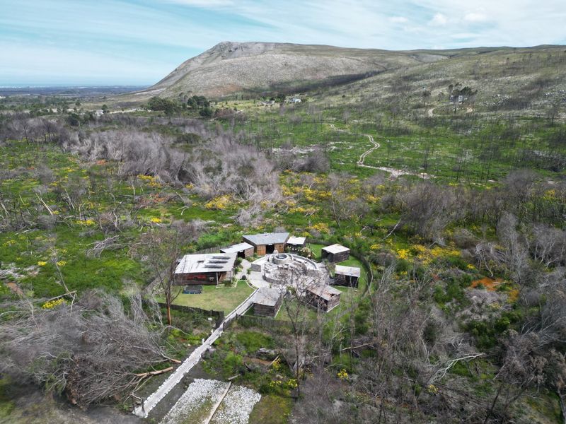 Aerial view of a rural farm property featuring multiple detached structures arranged around a central courtyard, set within a vast natural landscape.