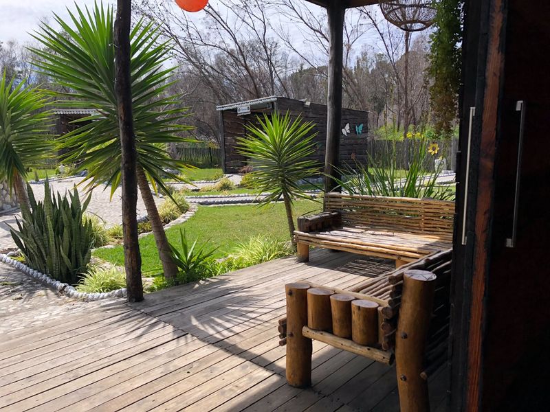 A rustic timber deck patio overlooking a landscaped garden area with mature plantings and wooden structures.