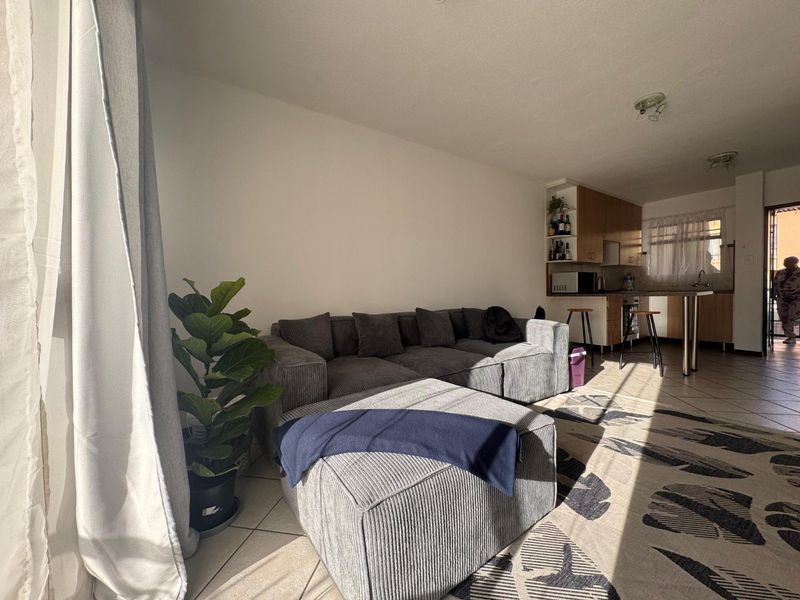 Open-plan living area featuring tiled flooring and a functional kitchen with built-in cabinetry and a breakfast bar.