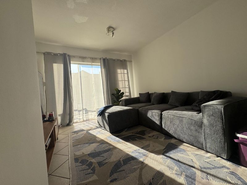 A living room featuring ceramic floor tiles and a sliding glass door leading to an outdoor area, with visible ceiling water staining.