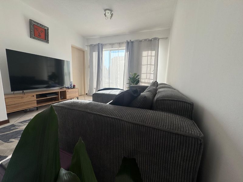 A comfortable living room featuring tiled flooring and a sliding glass door that provides natural light and access to the exterior.