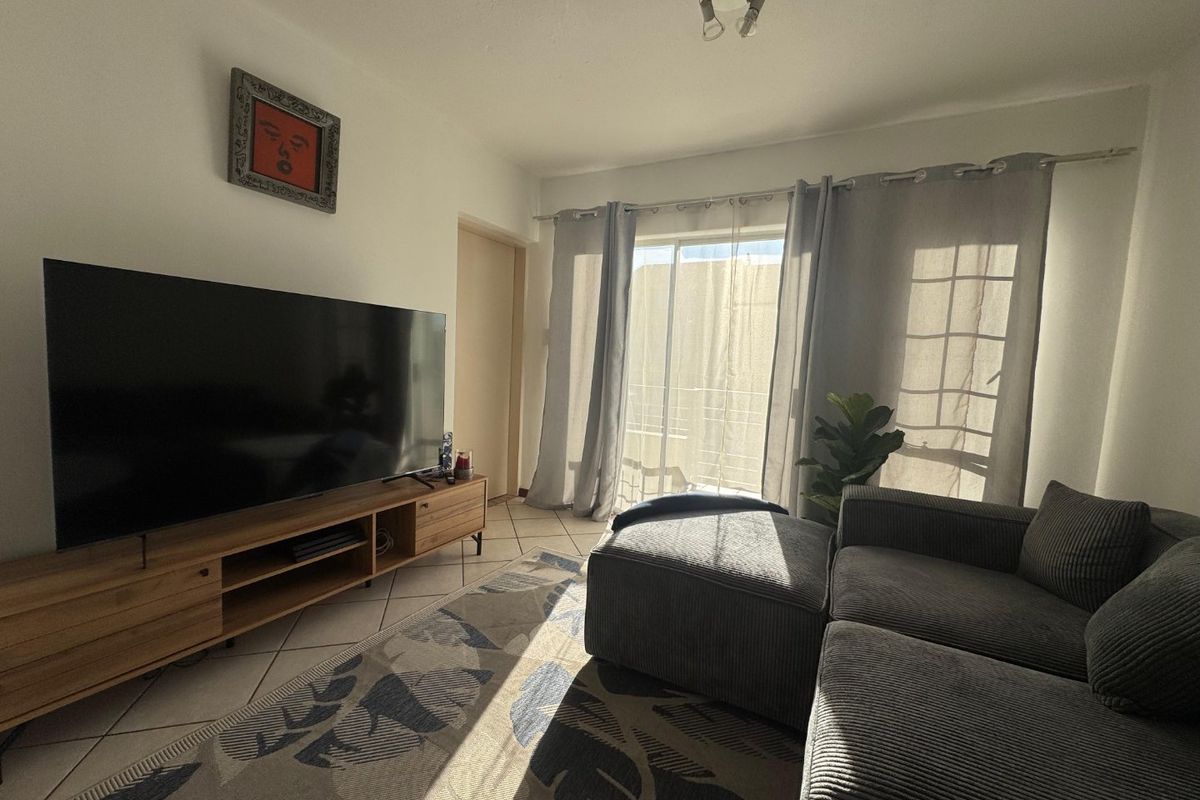 A comfortable living room featuring tiled flooring and a sliding glass door that provides natural light and access to the outdoor area.