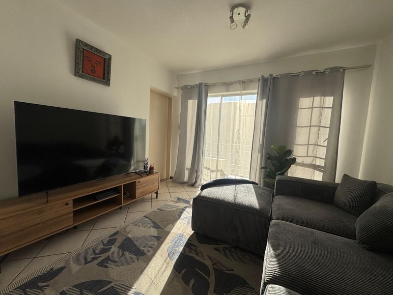 A comfortable living room featuring tiled flooring and a sliding glass door that provides natural light and access to the outdoor area.