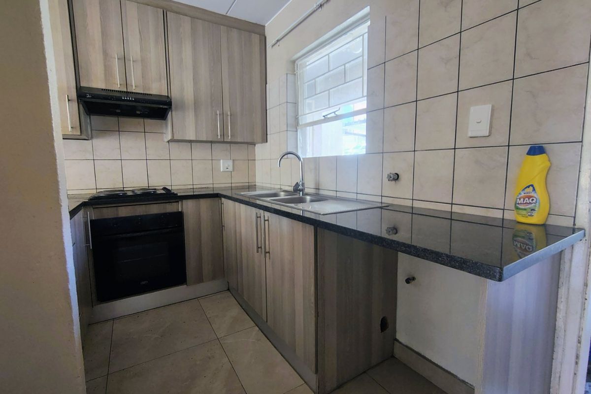 A functional kitchen featuring wood-look cabinetry, granite countertops, a built-in oven, and a tiled backsplash, offering a clean and practical workspace.