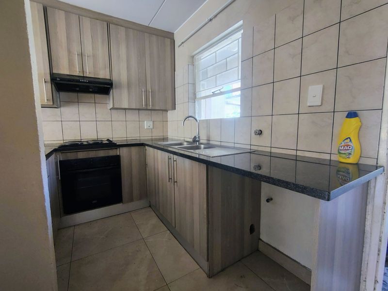 A functional kitchen featuring wood-look cabinetry, granite countertops, a built-in oven, and a tiled backsplash, offering a clean and practical workspace.