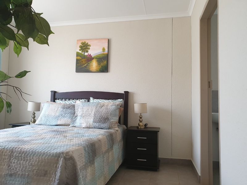 A bedroom featuring tiled flooring and cove cornicing, with an adjacent doorway leading to an en-suite area.