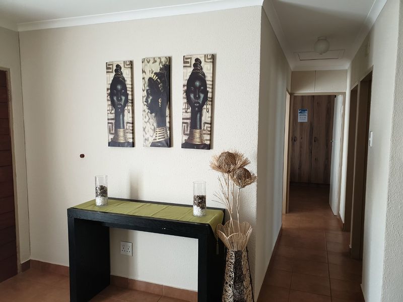 A functional hallway featuring tiled flooring, cove cornicing, and access to built-in storage cupboards.
