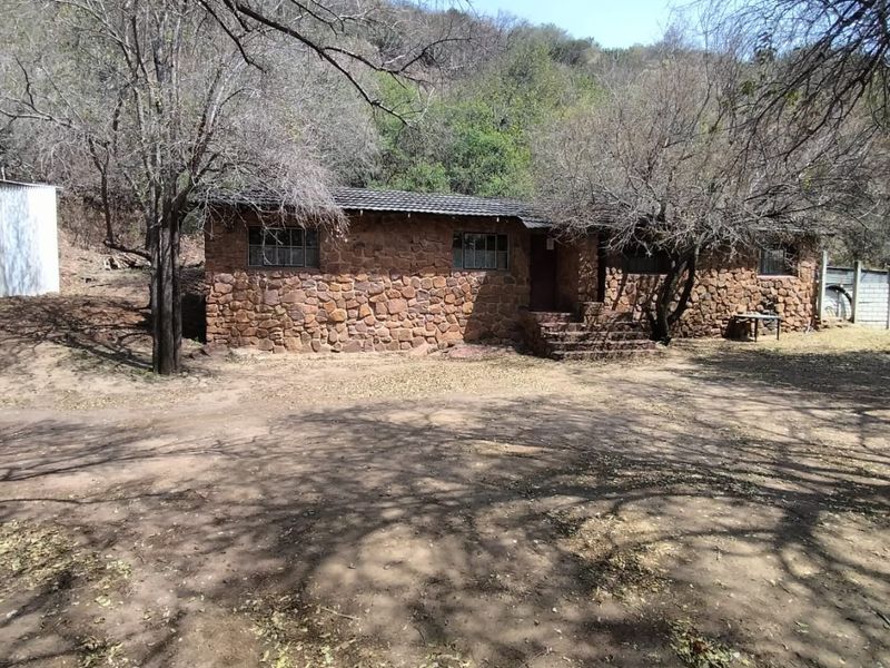 A rustic stone-clad farmhouse exterior featuring a tiled roof and natural landscape setting, showcasing a traditional rural architectural style.
