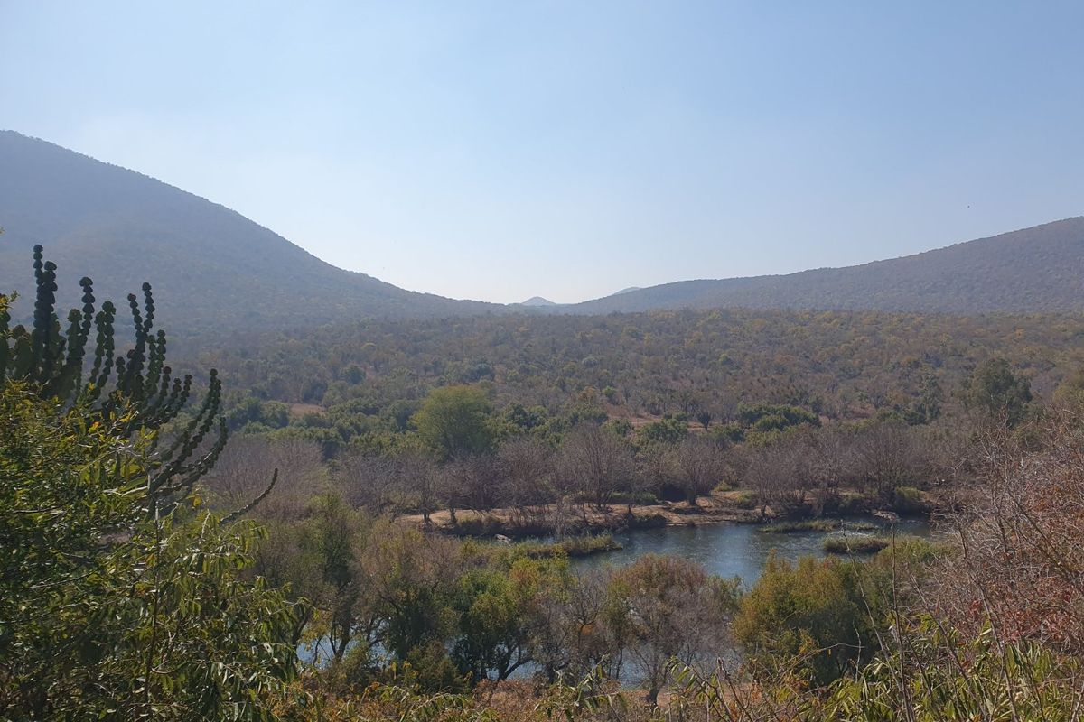 A scenic landscape view overlooking a natural river and surrounding hills, showcasing the property's expansive rural setting.