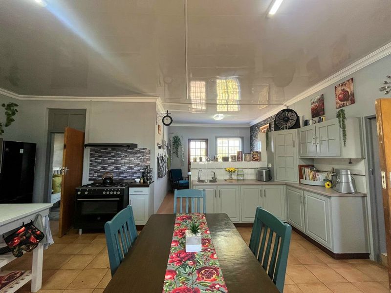 Open plan kitchen and dining area featuring built-in cabinetry, a gas stove with extractor, and tiled flooring throughout.