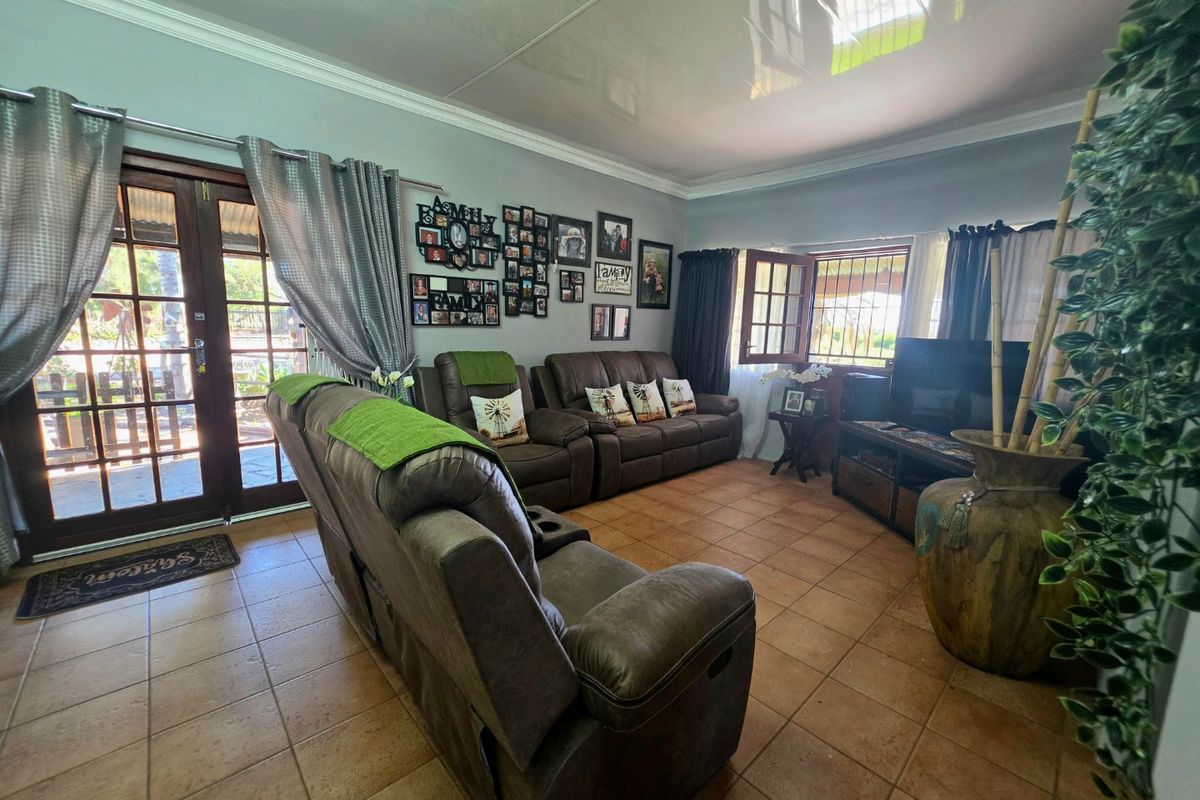A comfortable living room featuring tiled flooring, crown molding, and double glass doors providing access to the outdoor area.