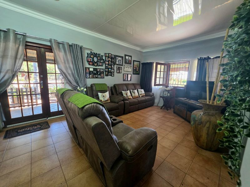 A comfortable living room featuring tiled flooring, crown molding, and double glass doors providing access to the outdoor area.
