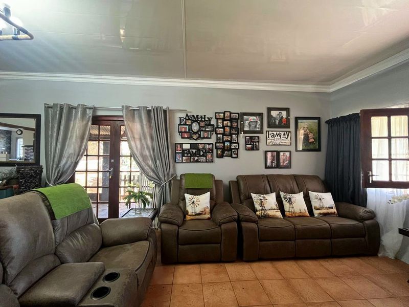 A comfortable living room featuring tiled flooring, coved ceiling cornices, and direct access to an outdoor area through a timber-framed glass door.