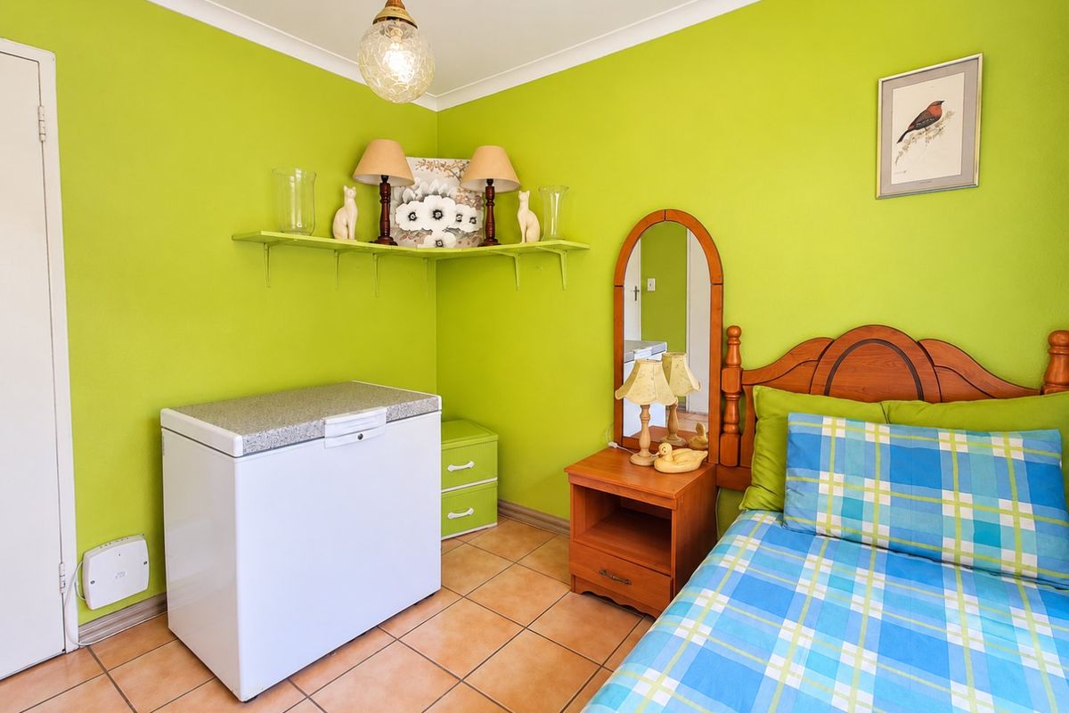A bedroom featuring tiled flooring, coving, and a pendant light fixture, currently decorated with bright green walls.