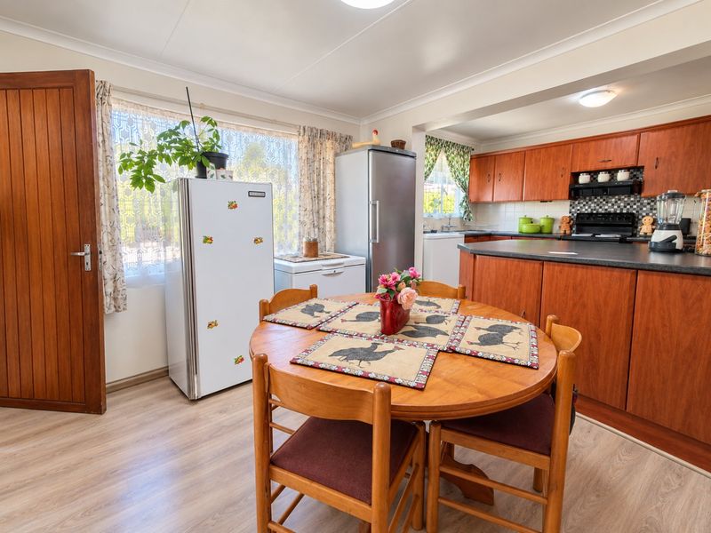 Open plan kitchen and dining area featuring wooden cabinetry, laminate countertops, and durable flooring, offering a functional layout for daily living.