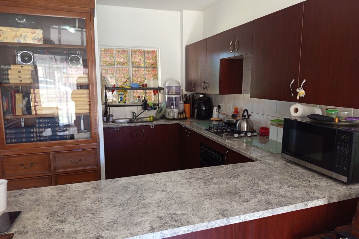 Functional kitchen featuring dark wood cabinetry, laminate countertops, a gas hob, and a tiled backsplash, offering a practical layout for daily cooking.