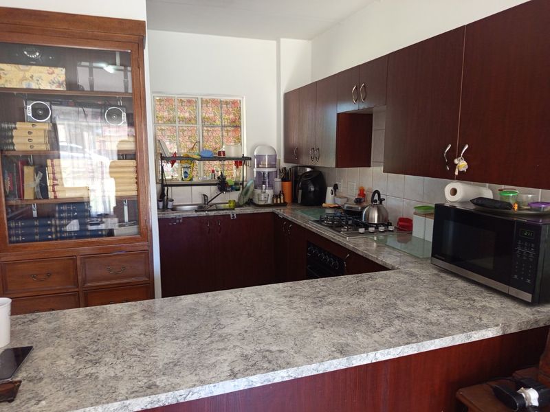 Functional kitchen featuring dark wood cabinetry, laminate countertops, a gas hob, and a tiled backsplash, offering a practical layout for daily cooking.