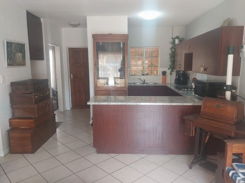 A functional kitchen featuring dark wood-look cabinetry, a breakfast bar, and tiled flooring, offering a traditional layout with potential for modern updates.