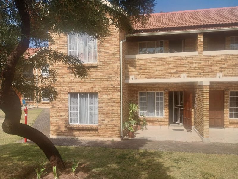 A two-story townhouse featuring a classic face brick exterior, tiled roof, and a ground-floor entrance with a security gate and paved walkway.