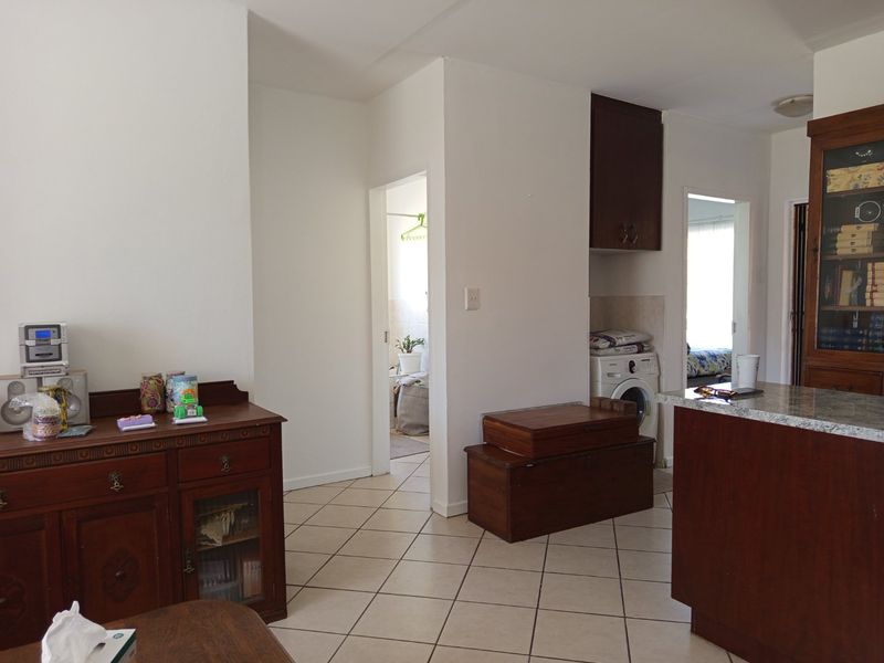 Open plan living area featuring tiled flooring, built-in cabinetry, and a granite countertop, with a dedicated laundry nook and access to adjacent rooms.