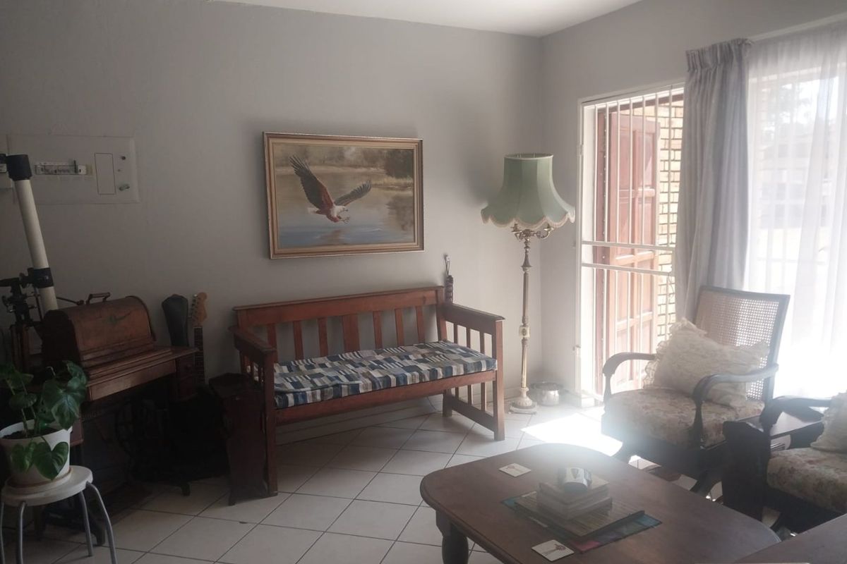 A living room featuring tiled flooring and a sliding door with a security gate, providing access to the exterior.