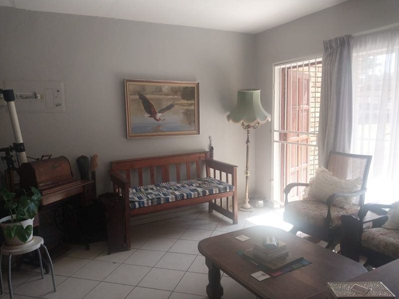 A living room featuring tiled flooring and a sliding door with a security gate, providing access to the exterior.