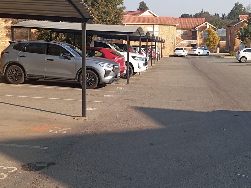 A view of the complex's designated covered parking area with multiple bays and paved driveway access.