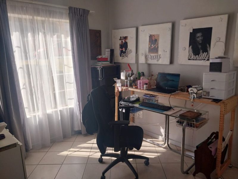 A functional home office space featuring tiled flooring and natural light from a large window, suitable for a dedicated workspace.