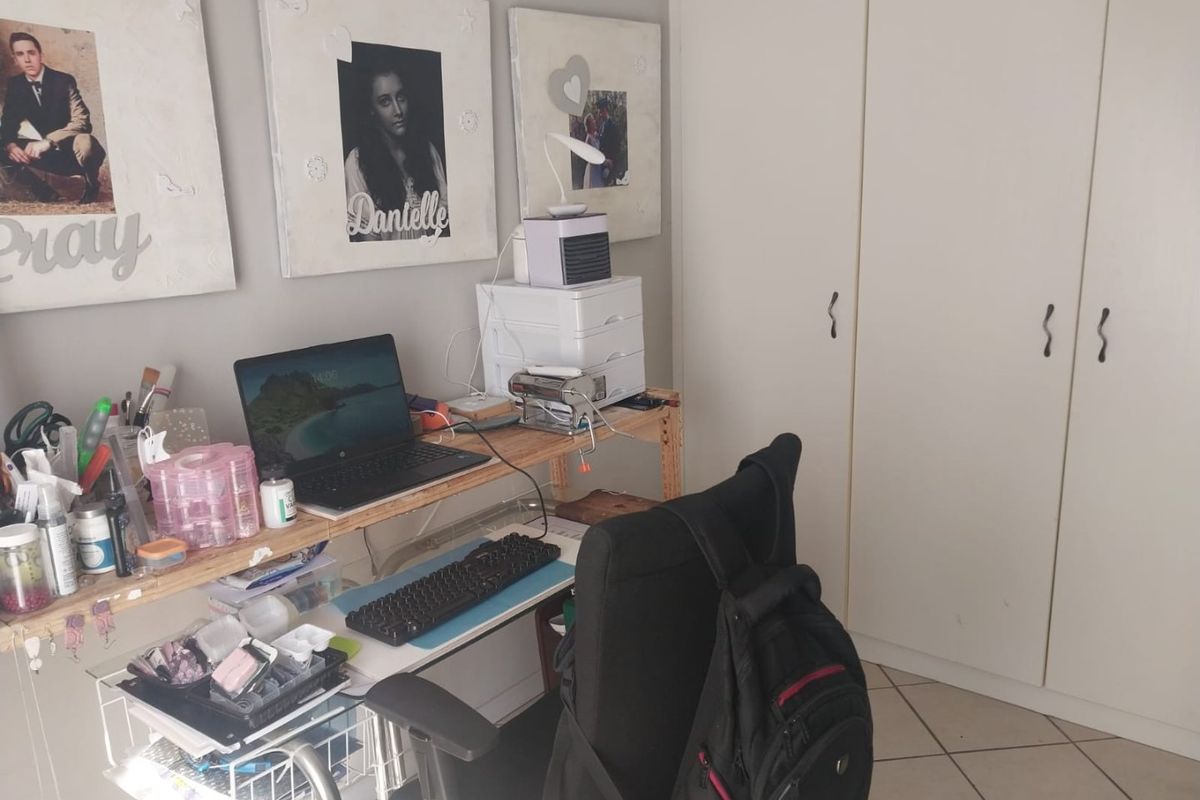 A bedroom featuring built-in cupboards and tiled flooring, currently utilized as a workspace.