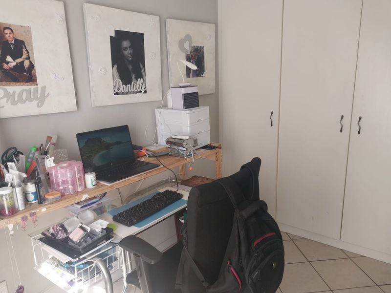 A bedroom featuring built-in cupboards and tiled flooring, currently utilized as a workspace.