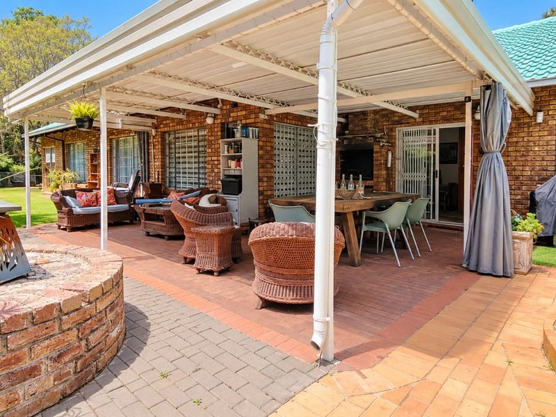 Spacious covered patio featuring brick paving, a built-in brick fire pit, and direct access to the home through sliding doors.