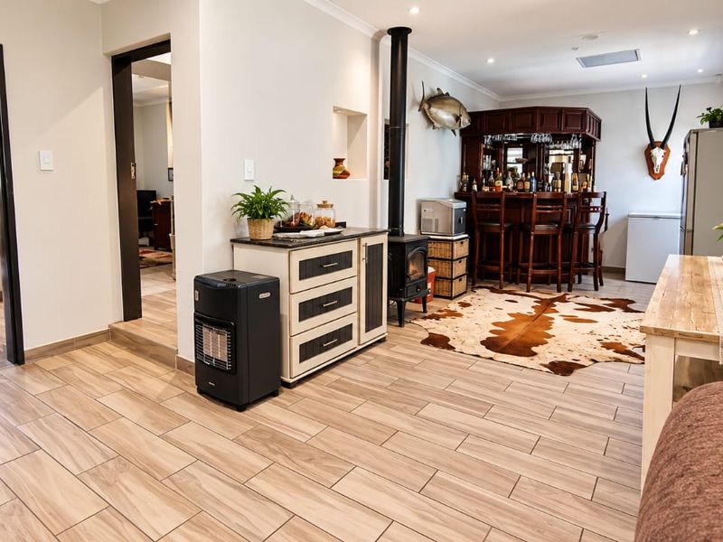 A spacious entertainment area featuring a built-in bar, a wood-burning stove, and modern tiled flooring, providing a comfortable space for hosting.
