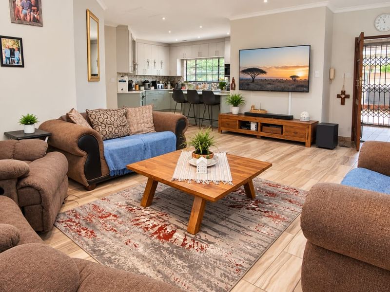 Spacious open-plan living area featuring tiled flooring, recessed lighting, and a modern kitchen with a central island, seamlessly connecting to the main living space.